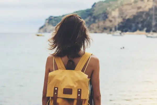 girl with backpack in sand coastline on nature landscape