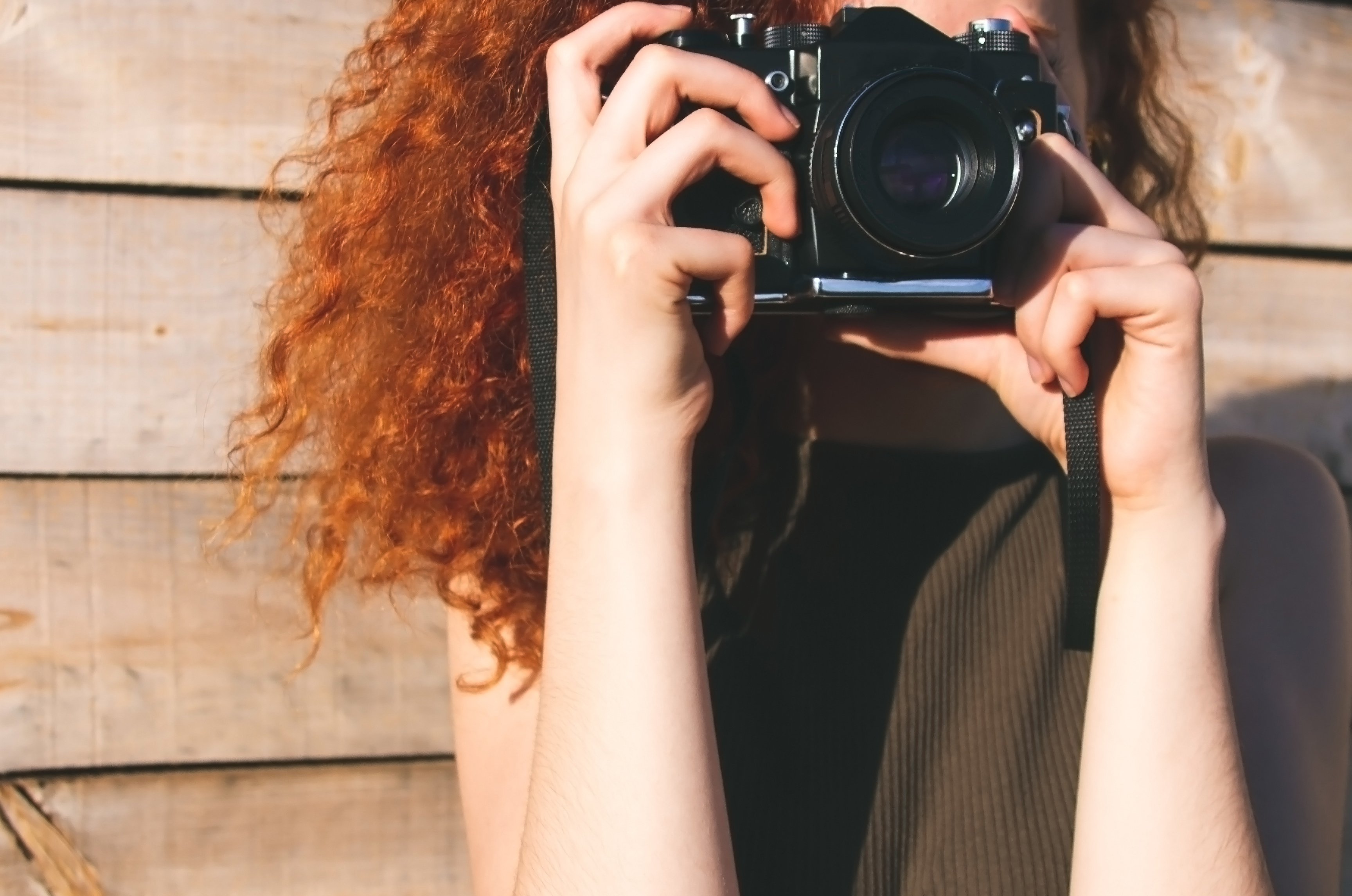 Young redhead photographer woman enjoying her passion outdoors